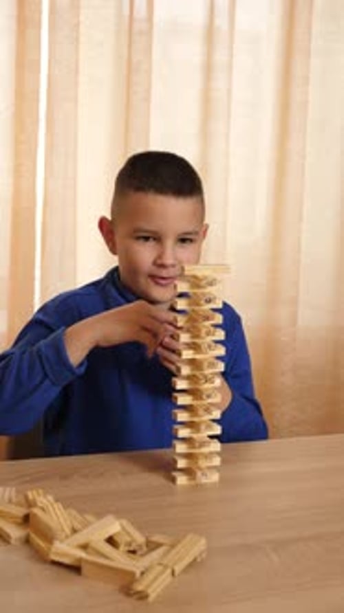 57A boy plays with wooden cubes, building different shapes.