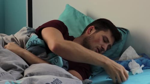 Sick Man Coughing in Bed Taking Medicine