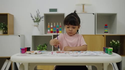 Little girl painting with watercolors at table