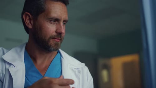 Smiling doctor listens patient heartbeat with stethoscope in hospital intensive care unit