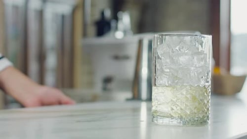 Bartender Stirring Cocktail with Ice in Glass at Bar