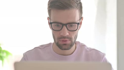 Close Up of Young Man Reacting to Loss on Laptop