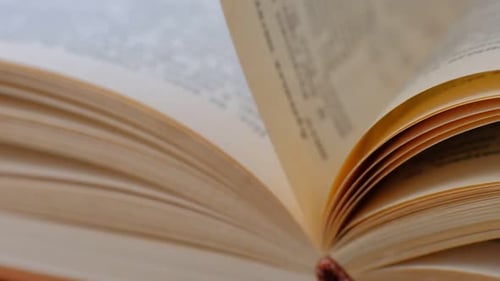 Nahaufnahme eines Buches mit Händen, die durch die Seiten blättern, Buchseiten öffnen, Zeitlupe