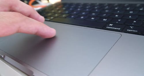 Amazing close-up slow motion shot of a young man's hand operating the trackpad of his Pro computer w