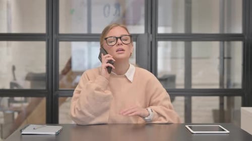 Angry Young Woman Talking on phone in Office