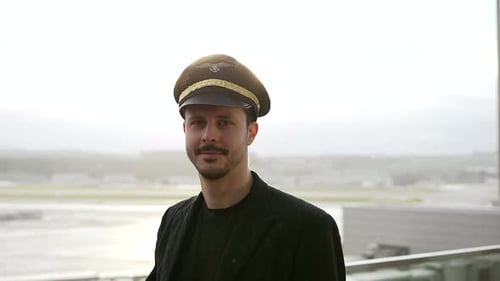 Young Man in Pilot's Hat Standing at Airport