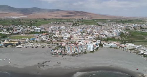 Aerial View of a Coastal Town with Beach, Mountains, and Urban Landscape