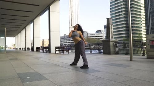 Creative camera movement spin with exotic hip hop dancer in city with big buildings sunny day