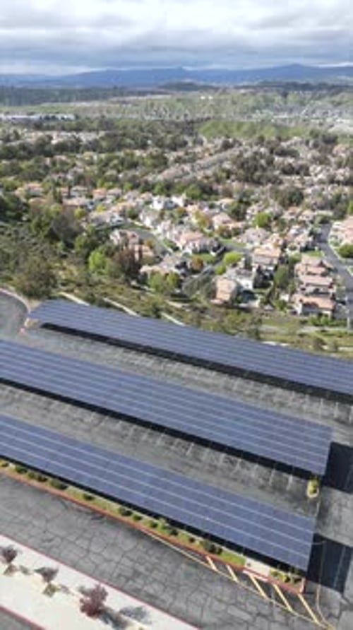 Solar Panels Overlooking a valley and foothill community - vertical, tilt down ascending drone view