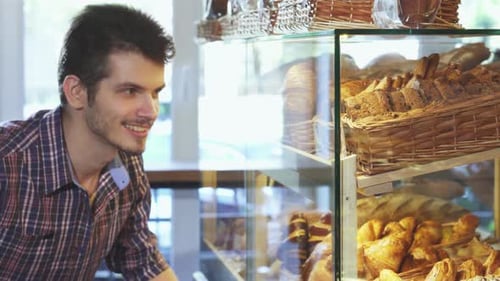 Charming Man Joyfully Selecting Pastries From a Bakery Showcase