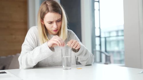 Close up of woman holding pills and glass of fresh water, taking medicine for headache, abdominal