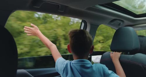 Handsome Satisfied Blond Teen Boy which Sticks His Hand Out of Car window