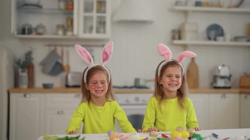 Zwillingsmädchen feiern Osterfeiertage Zwillinge lustige Kinder in Hasenohren springen aus dem