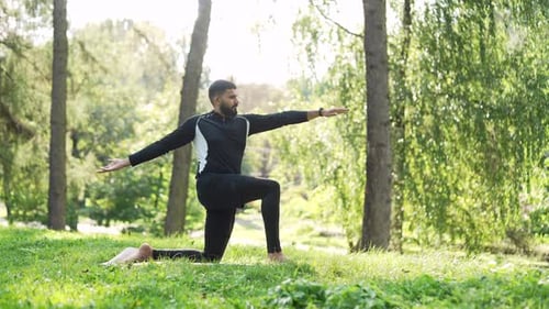 Ein
erwachsener Sportler turnt, während er barfuß auf einer Matte in einem städtischen Stadtpark steht. Sportlicher Rüde