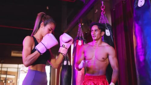 Asian young fitness trainer support sportswoman doing boxing in gym.