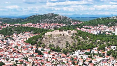 Historical Fortress Overlooking Ancient City Nestled Among Rolling Green Hills