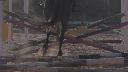 Nach oben kippbare Rückansicht einer Frau, die auf einem Pferd reitet und auf einer Ranch über eine Barriere springt. Zeitlupenaufnahme