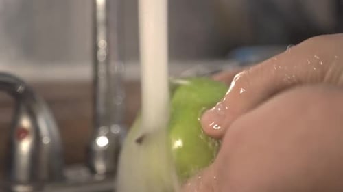 Meticulous Washing Of Green Apple Using Both Hands Under The Running Water. -close up shot