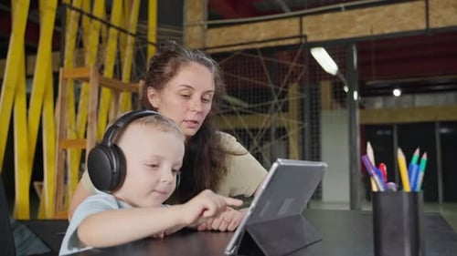 Woman and Child Use Tablet at Table
