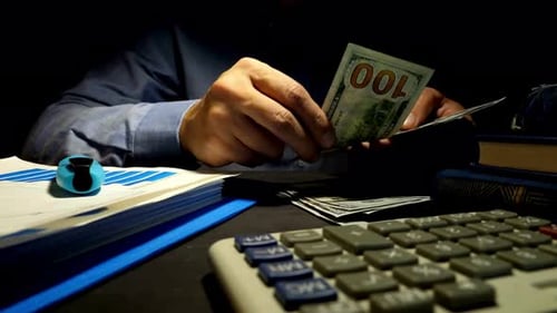 Man Counting Money in Dark Office at Night