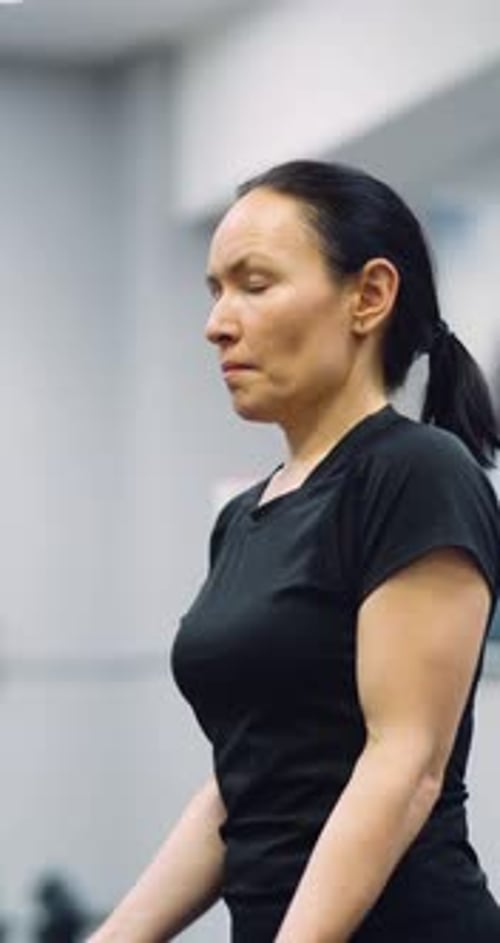 A Fit Middle Aged Woman Training Biceps with Dumbbells During an Intense Gym Workout