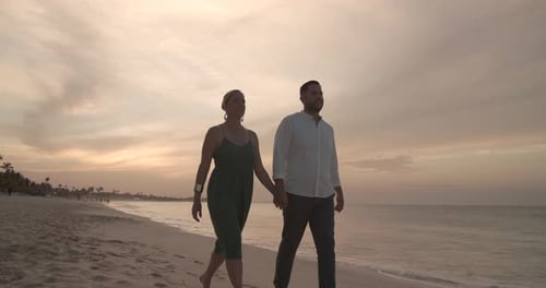 Romantic caribbean sunset beach walk of married couple holding hands in slow motion