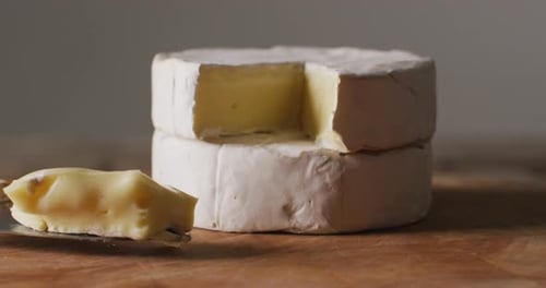 Video close up of soft cheeses and knife on wooden chopping board, with copy space