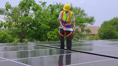 Engineer Inspecting Solar Panels on Bright Sunny Day