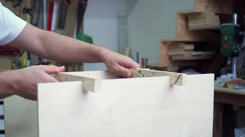 Professional woodworker handyman assembling a wooden crate in a busy workshop