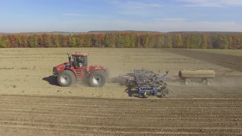 Big red tractor working on the field cultivating and applying nitrogen ASP