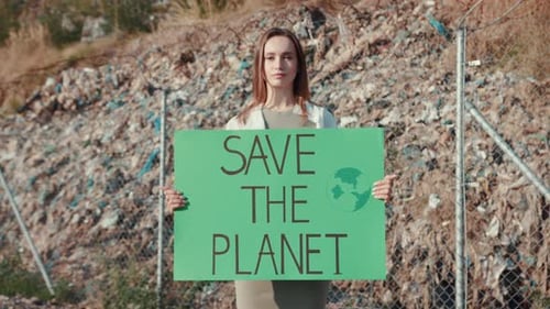 Woman Holding Save the Planet Sign at Landfill
