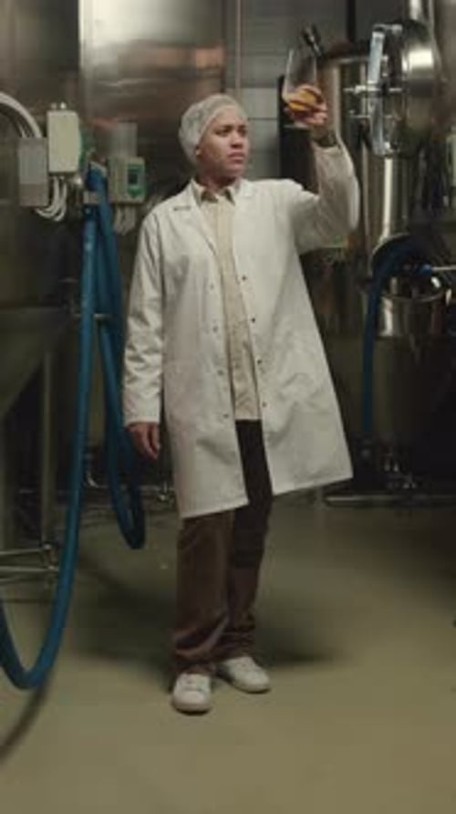 Researcher Inspects Amber Liquid Sample in Industrial Lab