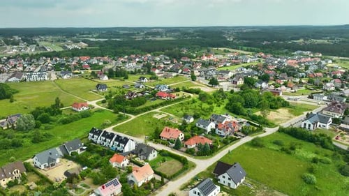 Aerial view of a suburban residential area with numerous houses, green spaces, and roads. The area i