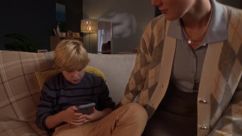 Woman comforting child using cell phone on couch