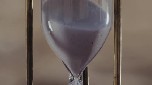 Hourglass, Sand hour. Big close Up, tilt down, sand pouring in hourglass. Outdoor, time passing conc