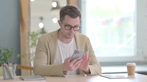 Joven empresario que usa un teléfono inteligente en el trabajo