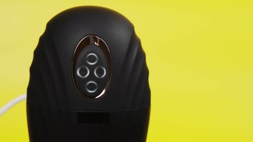 Sex toys for men. Artificial vagina for masturbation on a yellow background. Connected to charging,