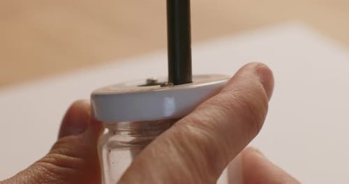 shot of using a pencil sharpener with the left hand. Static close up shot with shallow depth of fiel