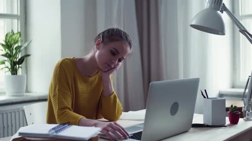 Tired Woman Works on Laptop at Desk