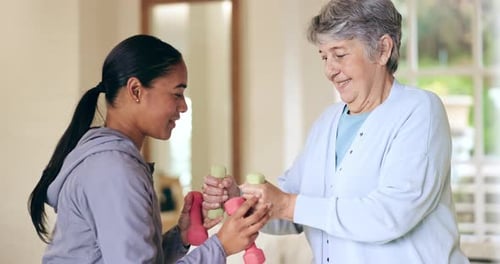 Young Adult Helping Senior Woman Exercise with Weights
