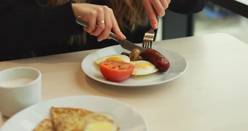 Woman Eating Breakfast with Eggs and Sausage