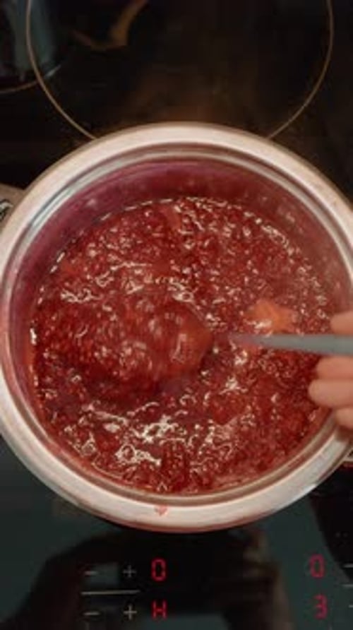 Vertical video Cooking homemade raspberry jam in the kitchen from fresh ingredients