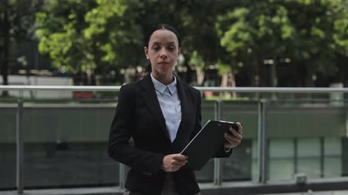 Confident Woman Holding Clipboard in Urban Setting
