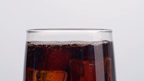 Close Up Of Ice Cubes Falling In A Glass Of Fresh Cola On White Background