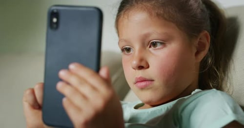 Child Engrossed Using a Smartphone Device Indoors