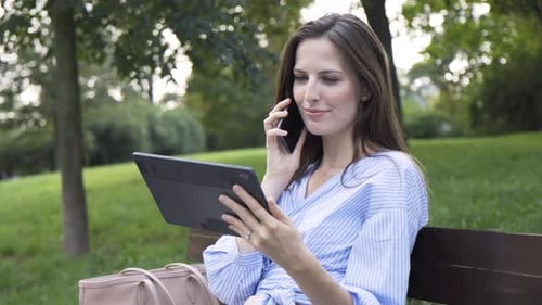 Woman Using Tablet and Mobile Phone in Park