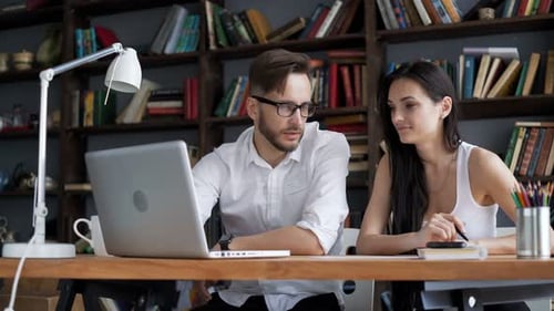 Two Students Brainstorming Work By Discuss With Desktop In Hipster Loft Closeup With Ground Books...