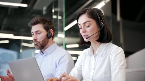 Customer service representatives working at desks with headsets in modern office. A team of call