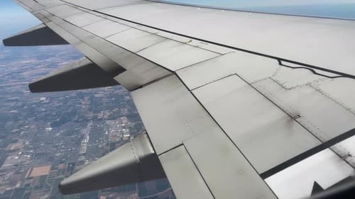 Pedestal-Tile Shot of a Beautiful View Out of an Airplane's Window on a Clear Blue Day While Flying