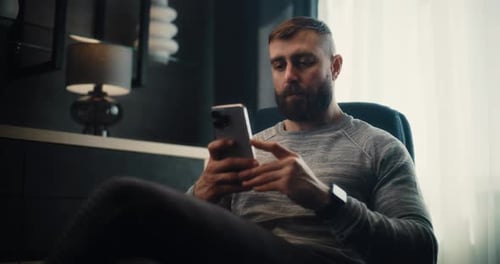 Stock Exchange Trader Analyzing Exchange Market Charts Using Smartphone in Cozy Office